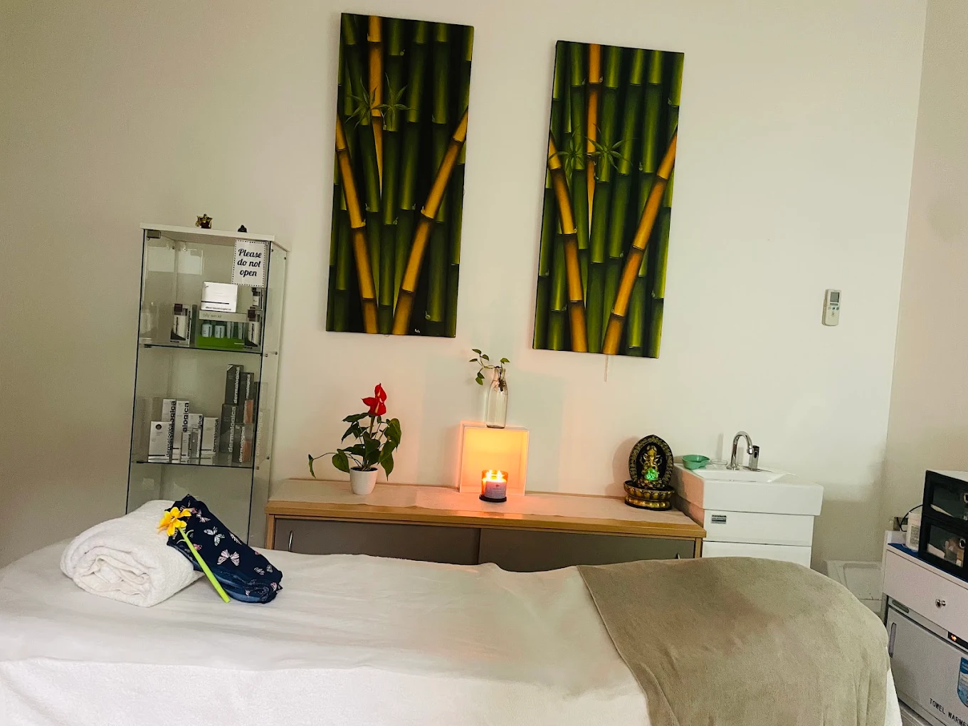Calm treatment room at Just ASK Hair & Beauty, Tuggerah — Dermalogica shelf, candles and bamboo artwork